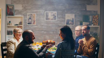 Excited young woman when her husband arrives with delicious cake