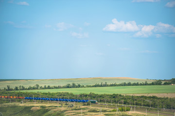 spring landscape with a railway on which a freight train is traveling