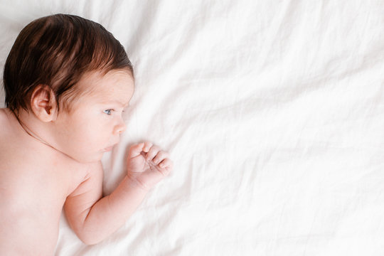 Baby newborn on white bed with copyspace