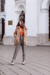 Fashion style portrait. beautiful stylish girl with long hair walks in the city. Portrait of attractive girl on the street. Spring or fall day. selective focus.