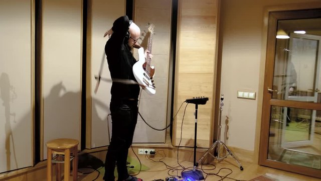 white man. Bald. on strike. Wearing a white guitar bass. Recording Studio.