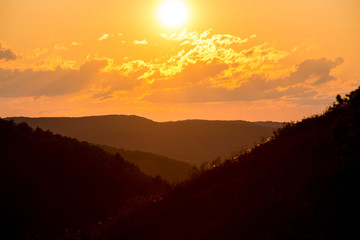 Fototapeta premium summer fiery red sunset in the mountains against the background of trees