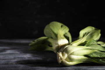 Fresh green bok choy or pac choi chinese cabbage on a gray wooden background. Dark, moody. Side view, copy space, selective focus.