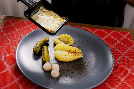 Swiss traditional dish called raclette including steamy potatoes, melted cheese and pickles eaten at christmas and wintertime