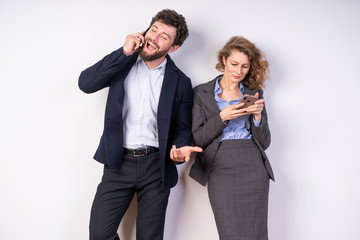 A young guy in business clothes, talking on the phone, gestured next to him, the girl looks to your smartphone