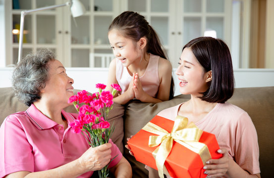 Happy Mother's Day  . Child And  Mother Congratulating Grandmother  Giving Her Flowers And  Gift Box