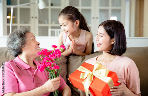 Happy mother's day  . Child and  mother congratulating grandmother  giving her flowers and  gift box