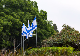White and blue ribbons on sky background. Flags and decorations for the independence day (Yom Haatzmaut) in an Israeli city.