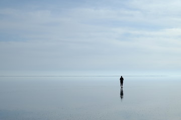 Lonely, thoughtful  man in the middle of sea watching horizon at sunset