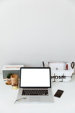 Top view of white office desk with laptop, smartphone, cup of coffee and supplies. Top view with copy space. Workspace with phone, laptop, flowers bouquet and glasses. Computer mockup white background