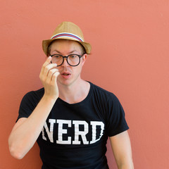 Portrait of young nerd tourist man touching eyeglasses