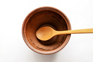 Close up of a round ceramic plate a brown bowl with a light wooden spoon on a white background