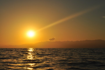 Atardecer en medio del mar con el sol poniéndose y cielo muy anaranjado en el horizonte
