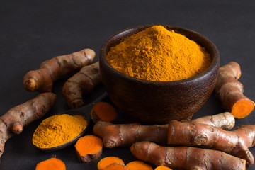 Turmeric (curcumin) powder and turmeric rhizomes on a wooden background,Use for cooking.