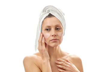 Beautiful woman with a towel on her head with patches for her eyes. White isolated background.