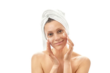 A young woman smears a white cream over her face with a large wipe. White isolated background.