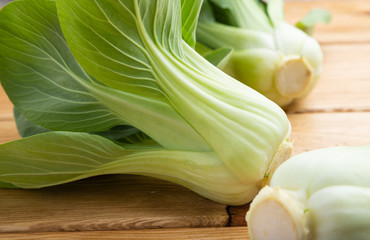 Fresh green bok choy or pac choi chinese cabbage on a brown wooden background. Side view.