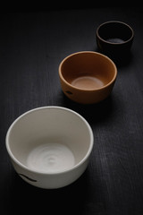 Obraz na płótnie Canvas Set of three handmade ceramic bowls. Matte black wood background.
