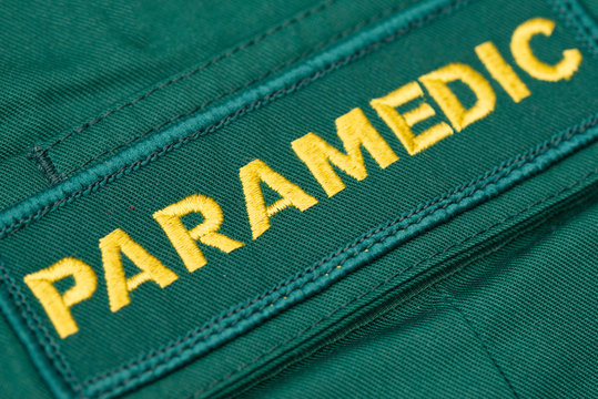 Kent, UK. 11th April 2020. Close up, angled view of a British PARAMEDIC badge sewn onto green paramedic shirt.