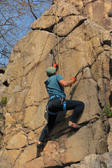 Rock climber man with ice axes, climbing a rock