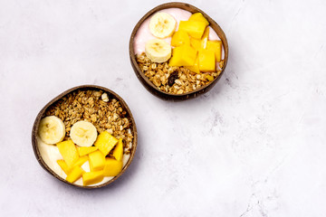 Tasty and Healthy Breakfast in Coconut Bowls Granola With Yogurt Banana and Mango Top View...