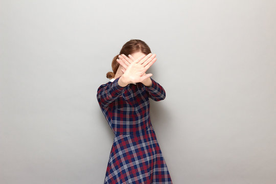 Portrait of girl stretching palms to camera and covering her face