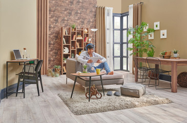 Man spending time at home, working, listenin music, brown room decoration style.