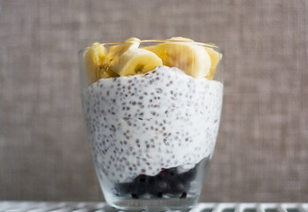 Background and two glasses with pudding chia, blackcurrant and fresh pieces of banana. Useful and delicious, with vitamins breakfast.