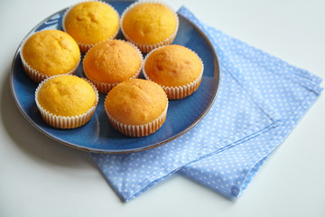 Pumpkin muffins on blue plate on white table with napkins, homemade bakery