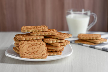 Shortbread cookies rectangular in a white square plate against the background of a mug of milk