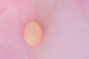 One pink Easter egg on a pink textured background