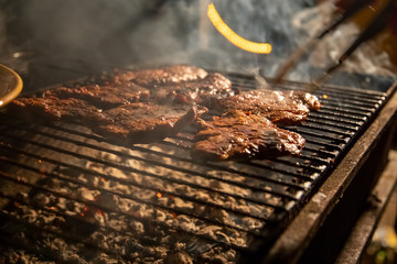in the evening a barbecue grill on which tasty juicy steaks are grilled over an open fire, a hand...