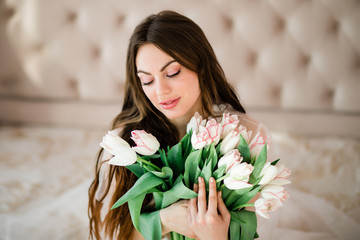 Young beautiful brunette woman holding a bouquet of white tulips. portrait of happy woman with flowers.