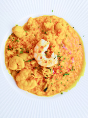 Tasty risotto with Shrimp, fresh herbs vegetables on a white plate