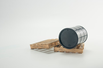 Black oil barrel on wood pallet with white background.