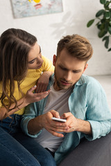 Woman talking to boyfriend with smartphone on couch