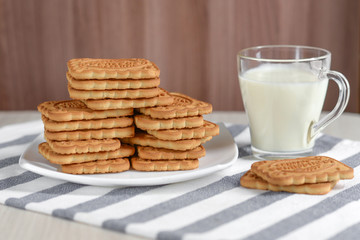 Shortbread cookies rectangular in a white square plate on a towel next to a mug of milk