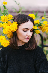 Beautiful girl in a black sweatshirt and with yellow flowersм