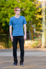 Full body shot of nerd man with red hair thinking in the park