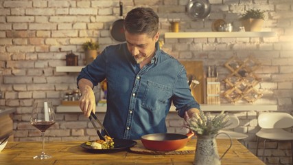 White casual man cooking in kitchen at home serving food to plate on dinner table