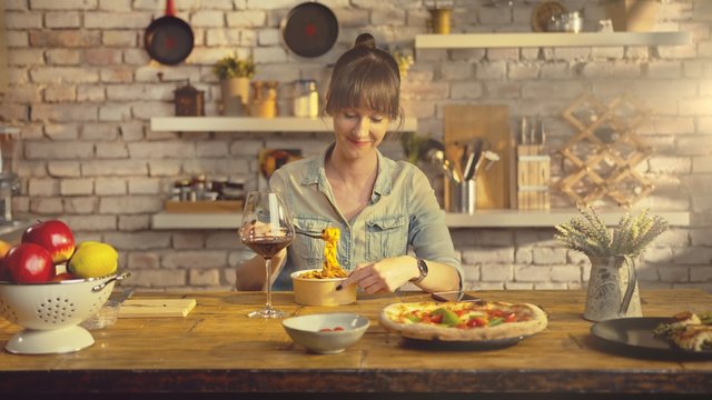 Casual White Woman Eating Take Away Pasta From Food Box At The Table In Kitchen At Home.