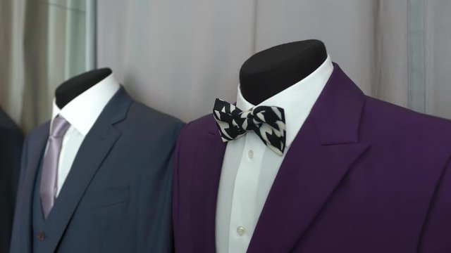 Two black manikins are standing in boutique. Stylish business formal clothing men. Lilac green jacket with white shirt and black bow-tie. Large selection of costumes. Business image for business men.