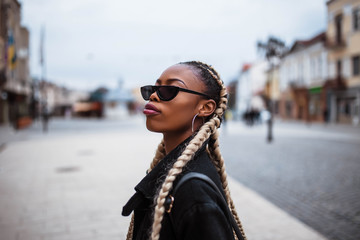 Obraz premium Portrait of african girl in the city. Black girl. Portrait in the city center. Girl wears glasses.