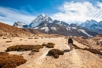 Young woman trekking in valley leading to the Everest base camp with Ama Dablam peak. Trekking in...