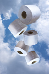 Five isolated toilet paper rolls on cloud background, vertical. Fun, light, bubbly, comic.