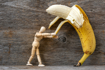 Wooden mannequin peeling a banana