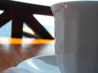 white cup closeup, design, on a wooden table, minimalism, on the background of boards, on the sea.