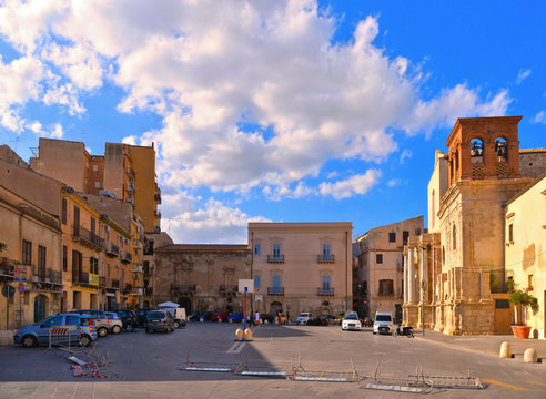  little square with old classical colorful buildings, church dome and cloudy blue sky in coastal town Licata in Sicily, Italy