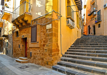 View of a narrow street with steps, old buildings and facades in the historical city of Agrigento in Sicily, Italy