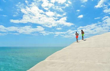 Cercles muraux Scala dei Turchi, Sicile Deux hommes sur un rocher de carlin lisse blanc regardant sur un horizon vide dans une plage bleue paradisiaque avec une eau turquoise christale et un ciel d& 39 été bleu nuageux à Scala Dei Turchi Agrigente, Sicile Italie